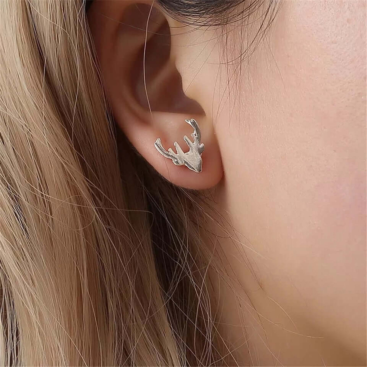 Silver deer antler stud earring shown worn on the ear.