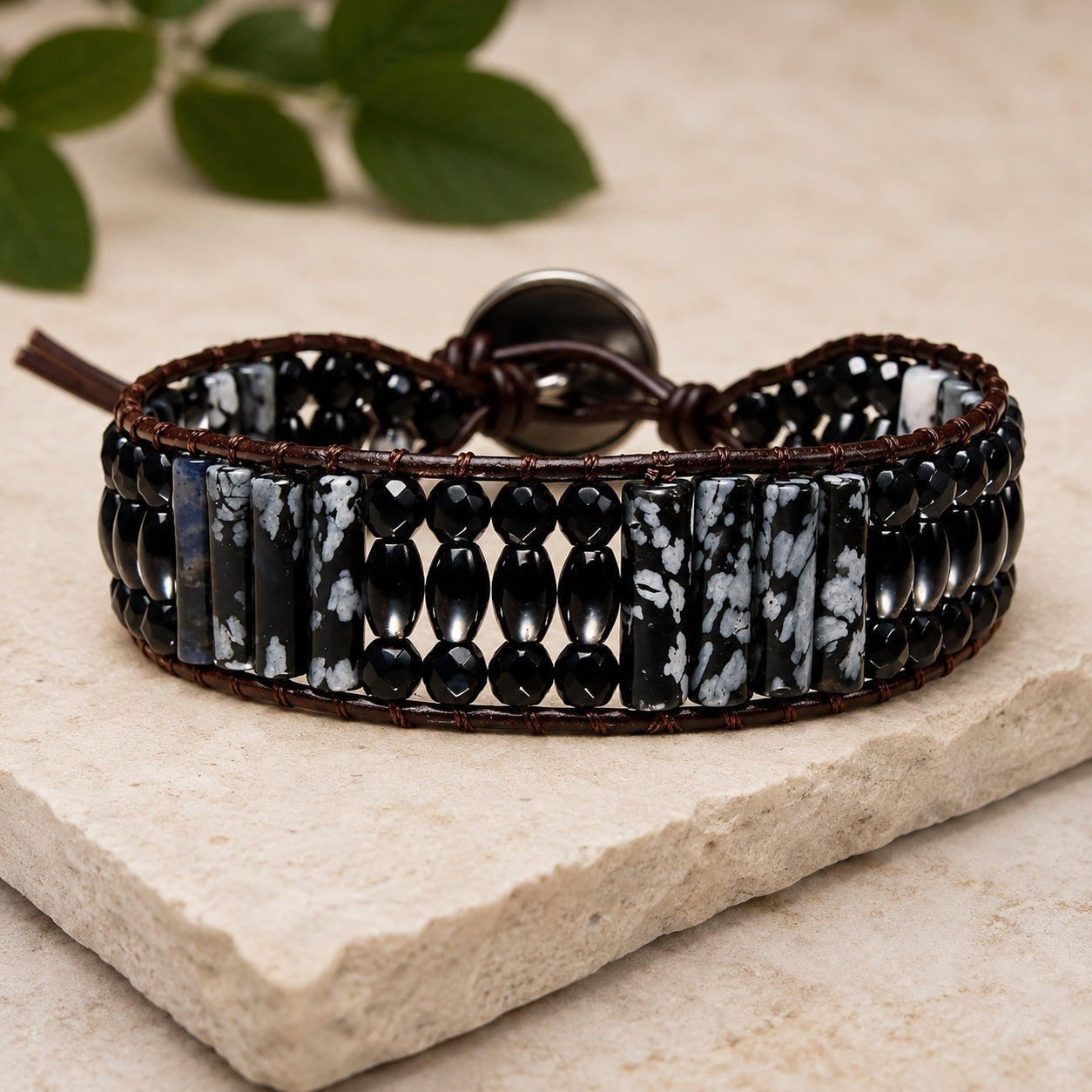 Snowflake Obsidian Bracelet displayed on a natural stone slab with polished black and snowflake obsidian beads.