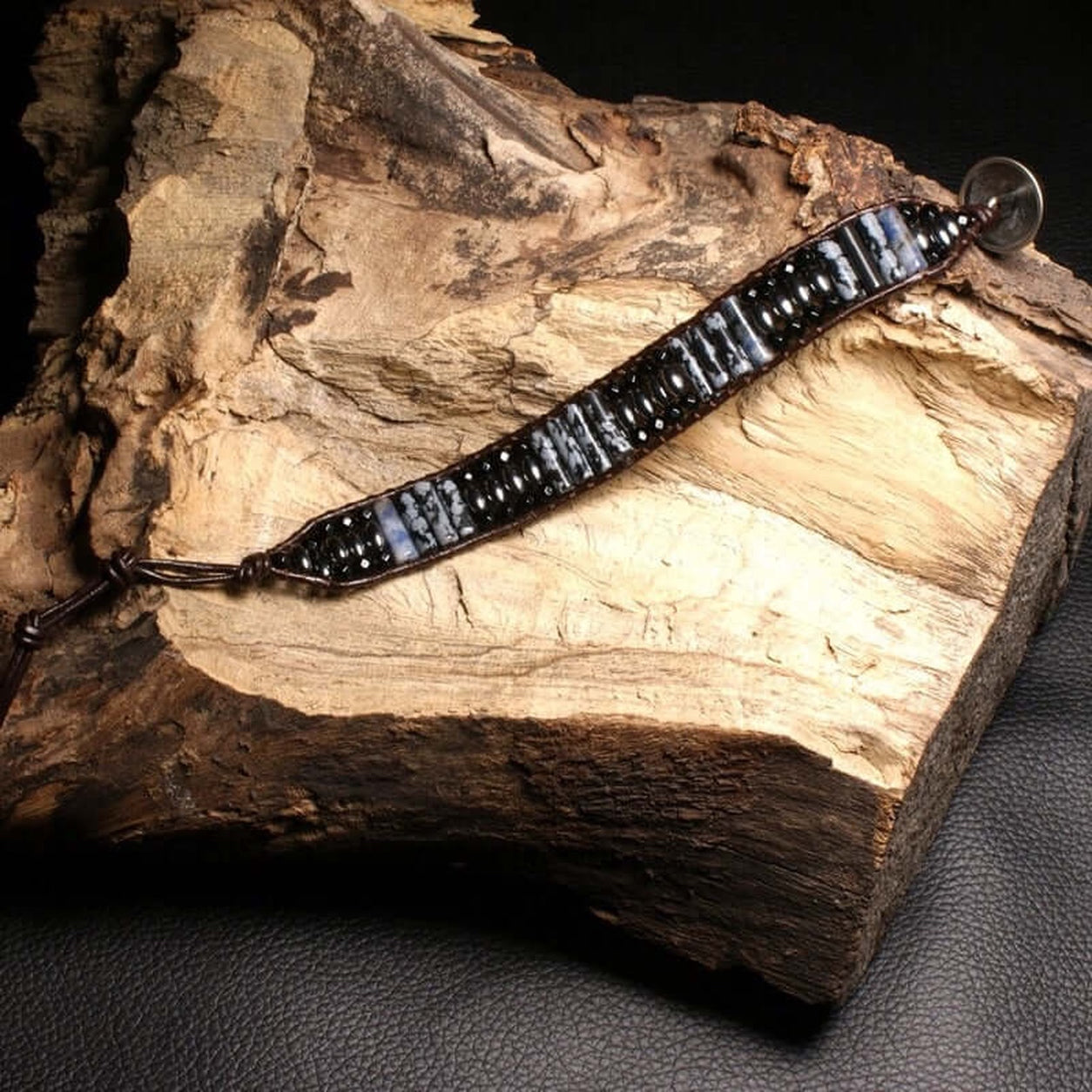 Full view of the handcrafted Snowflake Obsidian Bracelet displayed on natural wood.