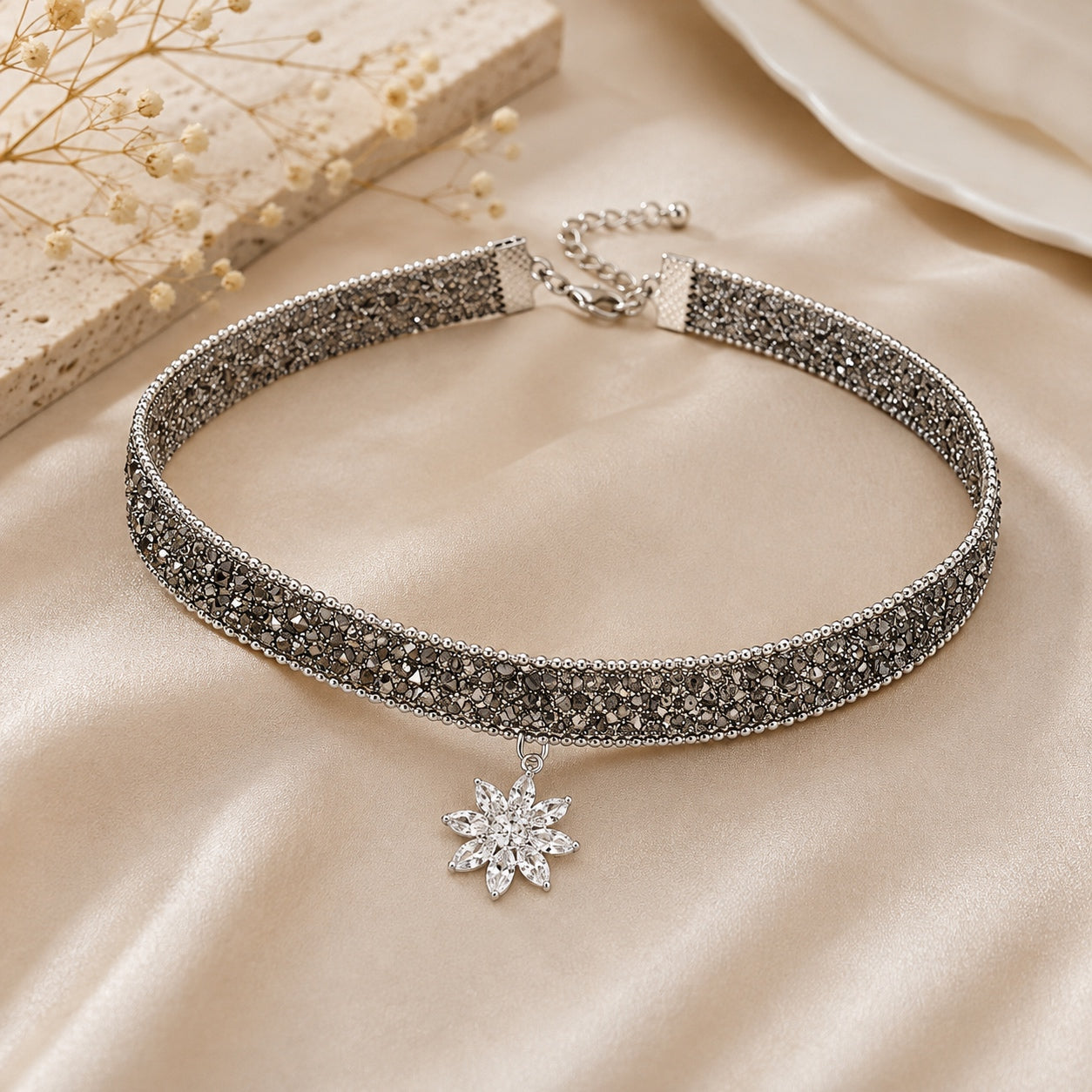 Angled view of the Sparkle Flower Choker Necklace with silver crystal detailing and a floral pendant on a soft satin background.