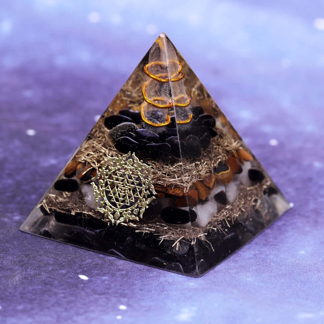 Angled view of the Sri Yantra Tiger’s Eye Crystal Pyramid with Black Obsidian, Clear Quartz, copper spiral and polished resin finish.