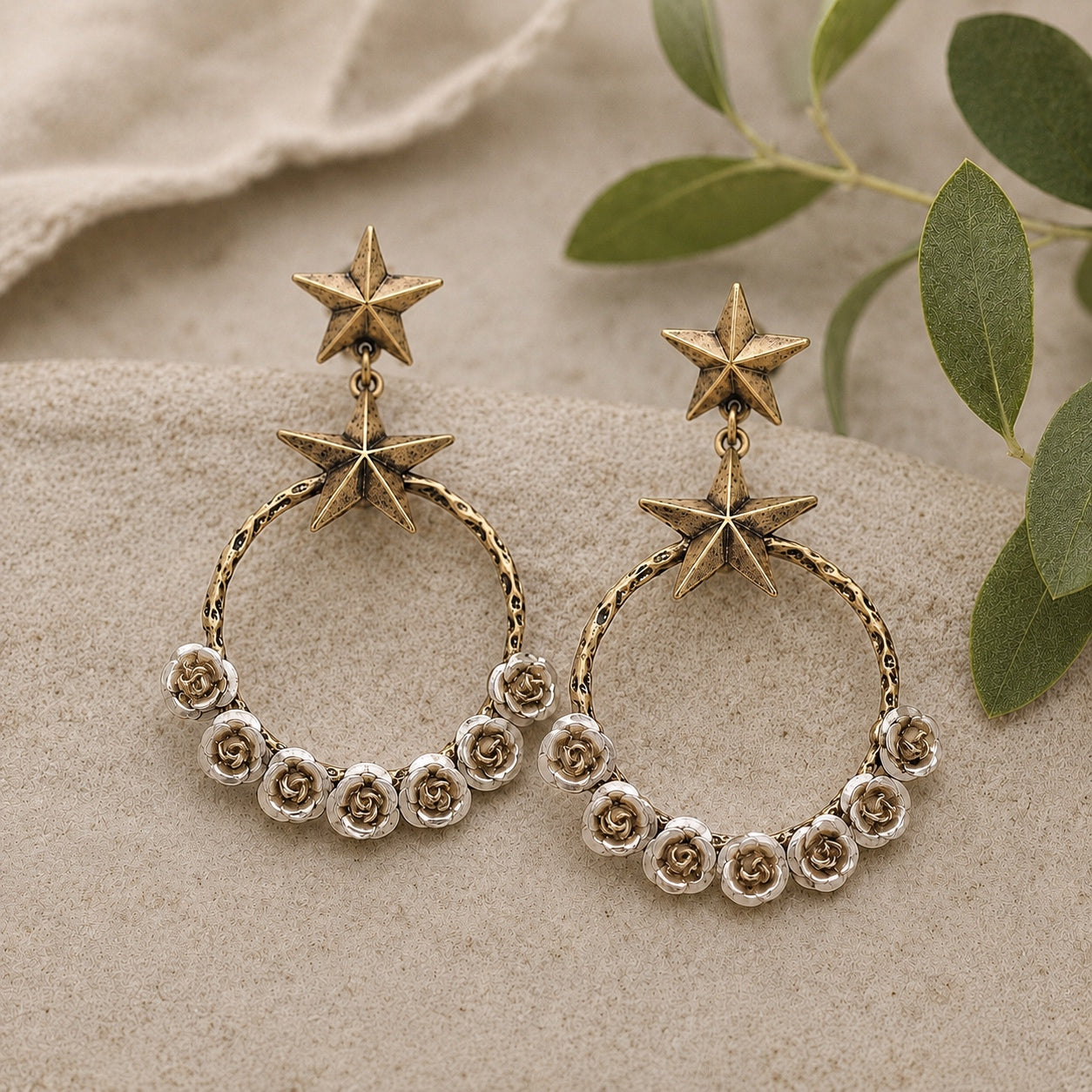 Starry Desert Rose Earrings featuring antique gold star studs with silver rose floral hoop dangle earrings on a neutral linen background.