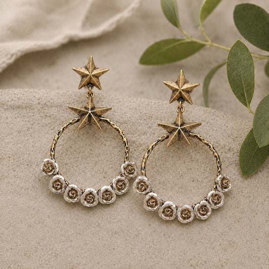 Starry Desert Rose Earrings featuring antique gold star studs with silver rose floral hoop dangle earrings on a neutral linen background.