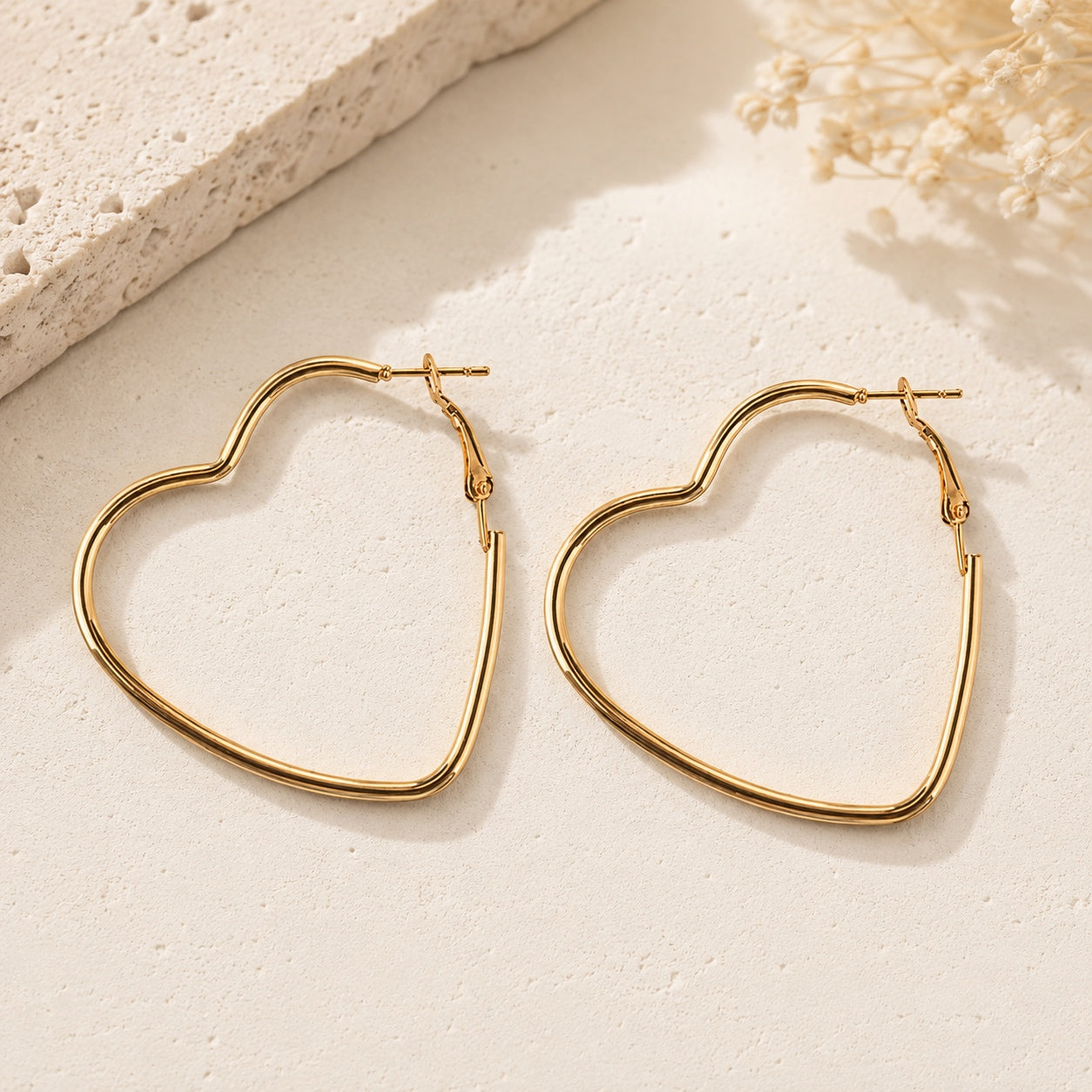 Timeless Heart Hoop Earrings, gold heart-shaped hoops on a textured neutral background.