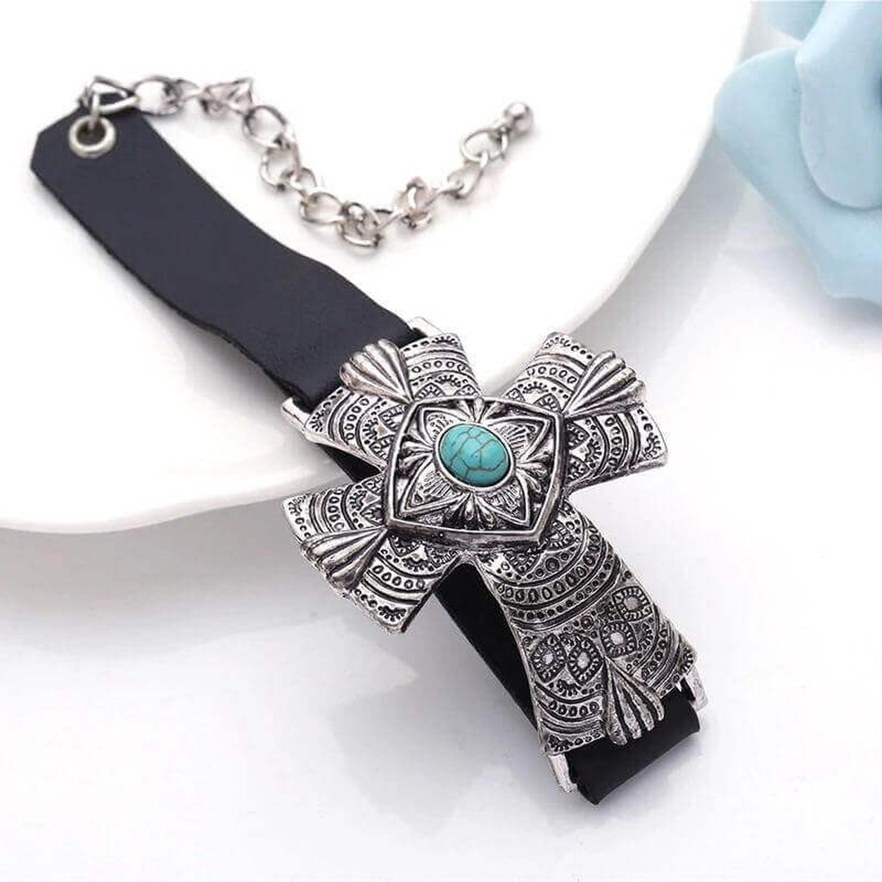 Turquoise Cross Statement Bracelet featuring an engraved silver cross with a turquoise stone centerpiece on a black leather band.