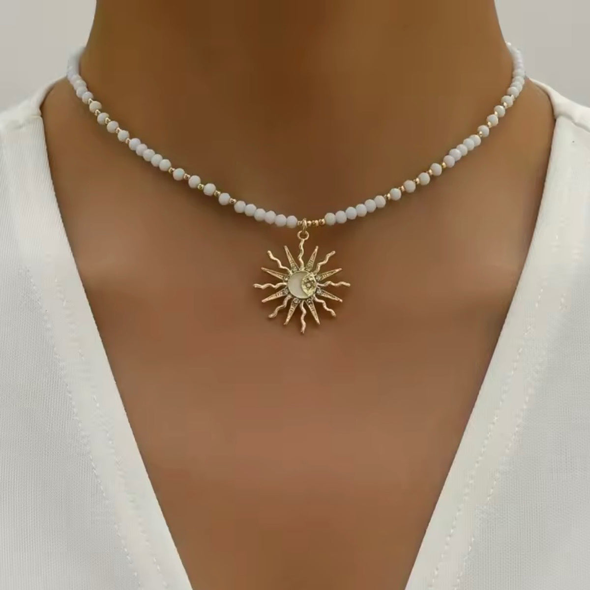 White beaded celestial sun necklace with gold-tone accents and a sunburst pendant featuring a crescent moon.