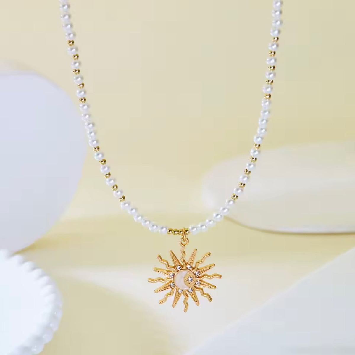Close-up of a white beaded sun pendant necklace featuring gold-tone accents and a detailed celestial sunburst charm.