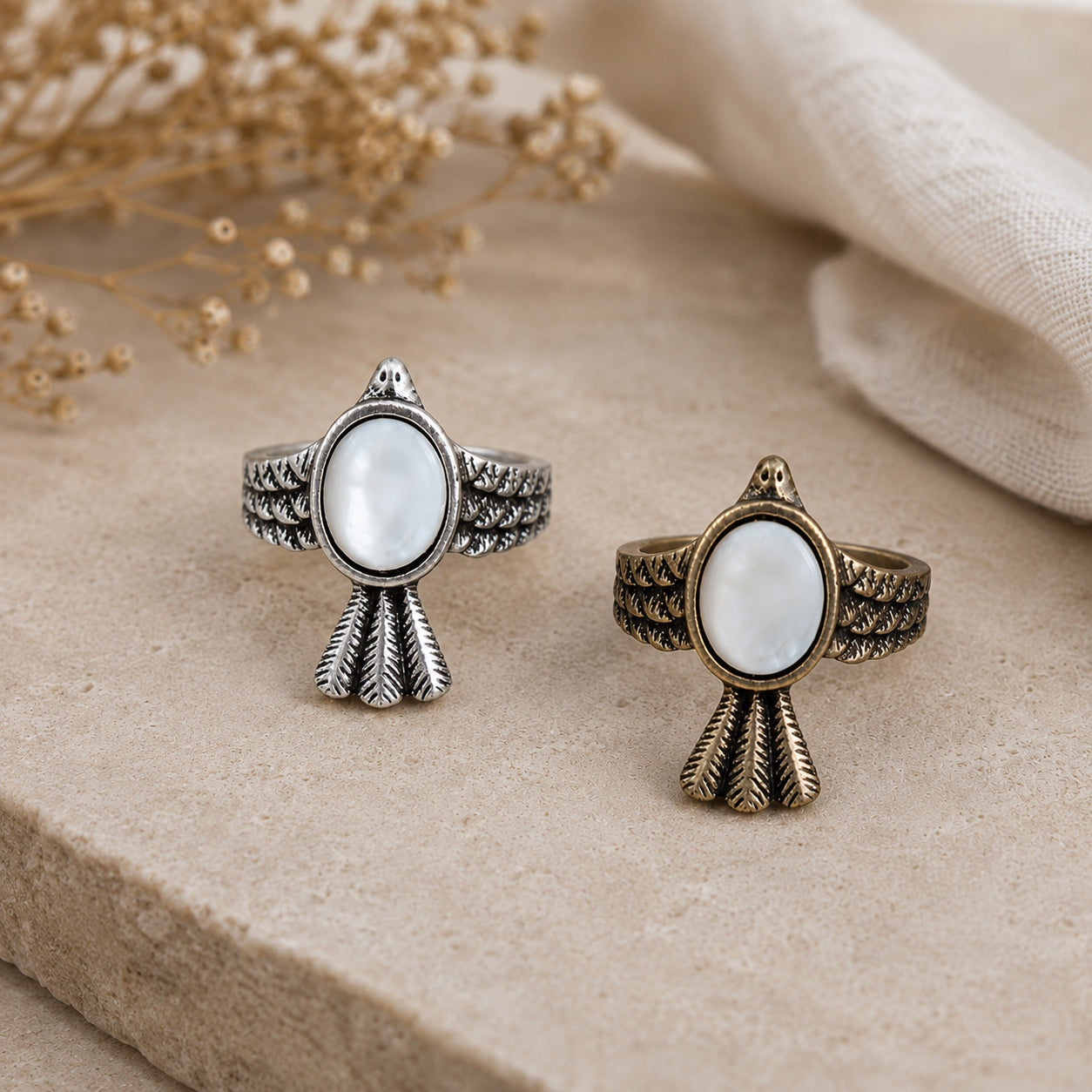 White Jade Bird Ring Set featuring antique silver and antique bronze bird rings with oval white jade stones on a neutral stone surface.