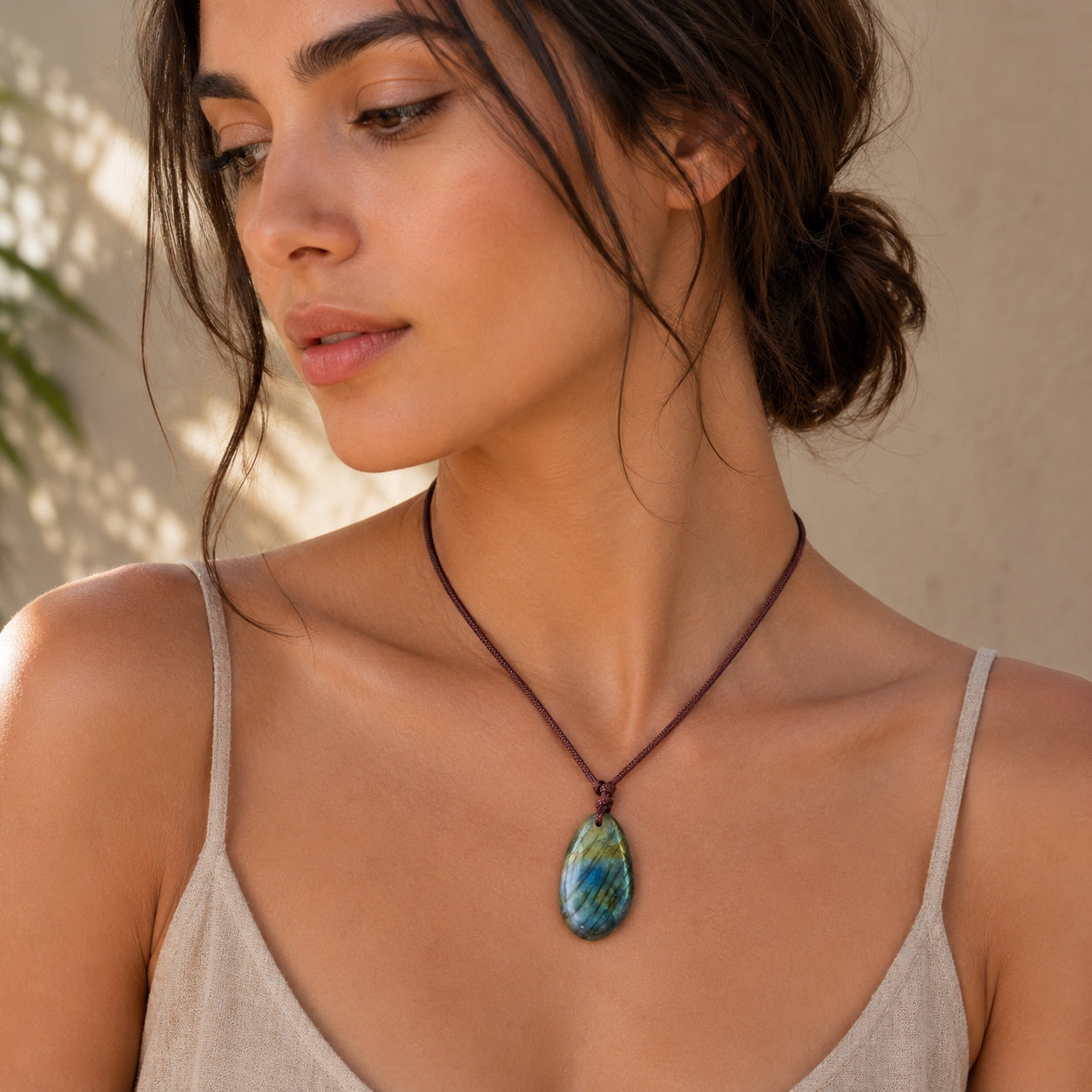 Woman wearing a Labradorite Stone Necklace featuring a polished natural gemstone pendant on an adjustable brown cord.