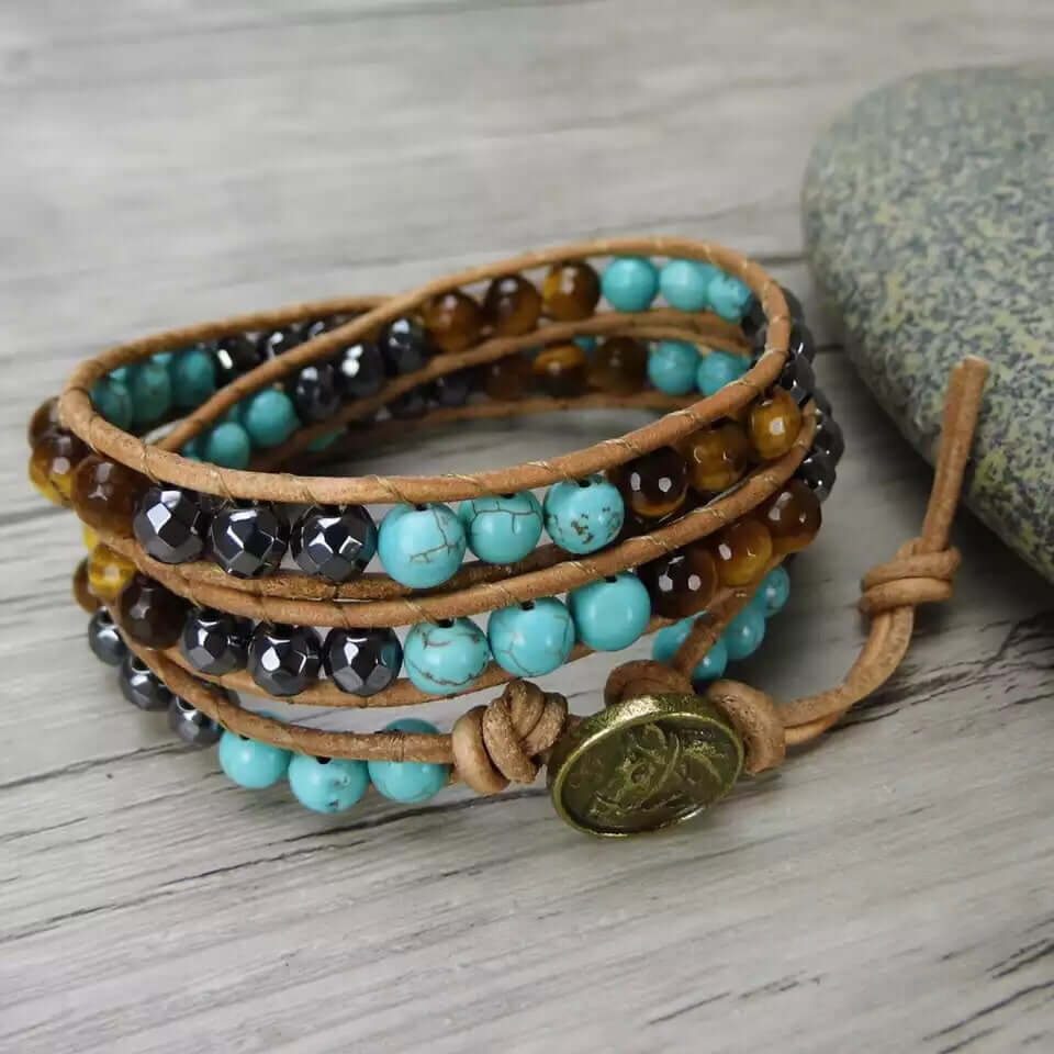 Angled view of the Spirit Of The West Bracelet featuring turquoise, tiger eye and hematite beads with rustic leather wrap design.